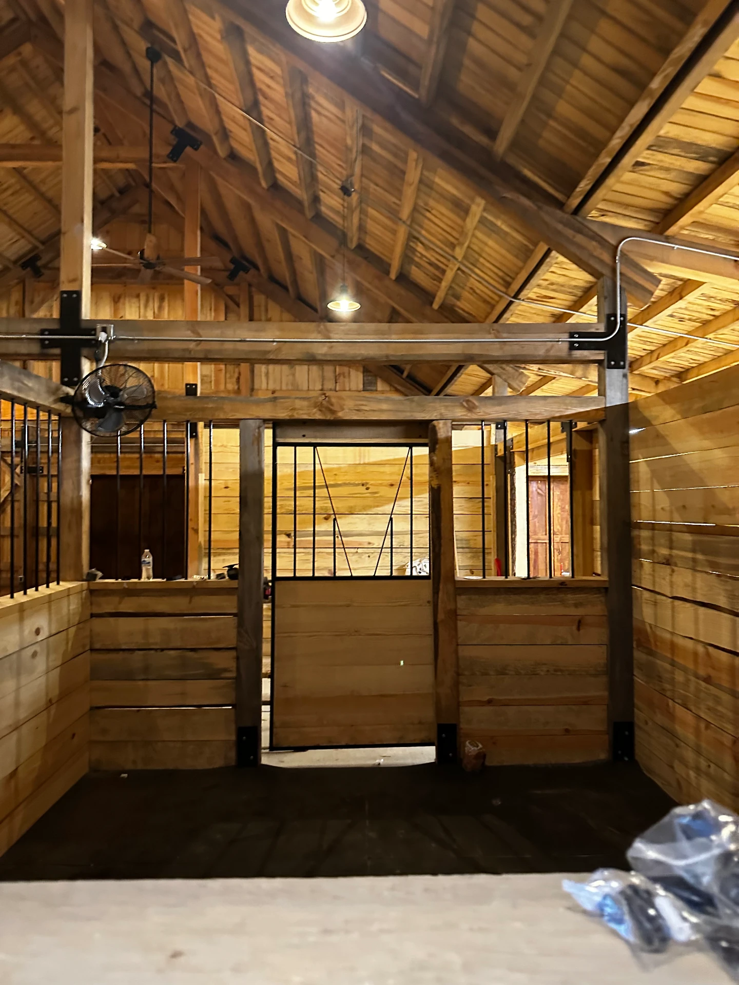 Interior of a finished timber frame barn with stall doors and exposed trusses