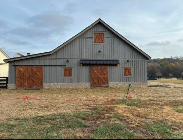 Gray board and batten barn with stained wood sliding doors