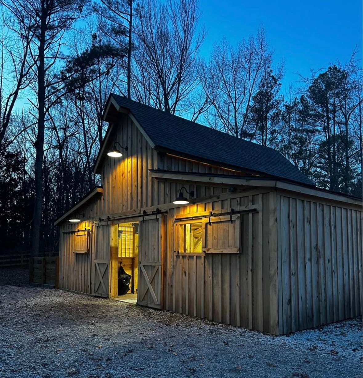 Barn at dusk with warm interior lights glowing through open doors
